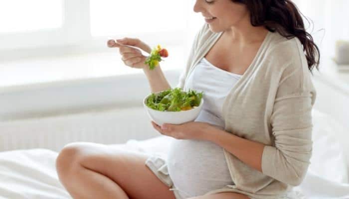 pregnant woman eating a bowl of superfoods for pregnancy