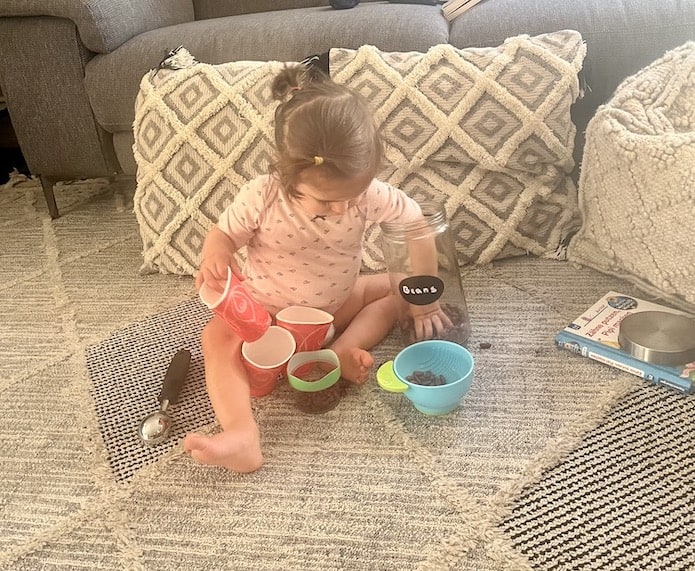 toddler having sensory play with beans