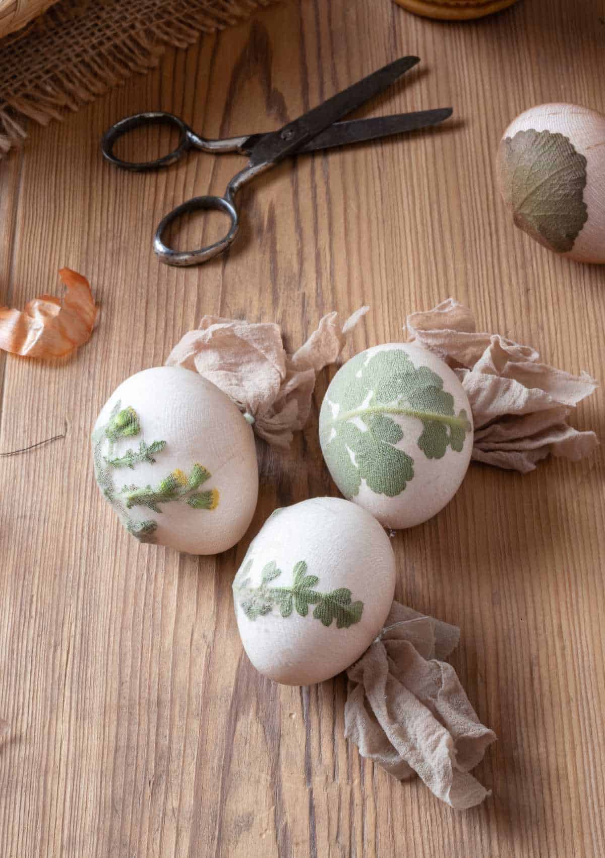 Easter eggs wrapped in cheesecloth with flowers and herbs for an onion skin dye bath