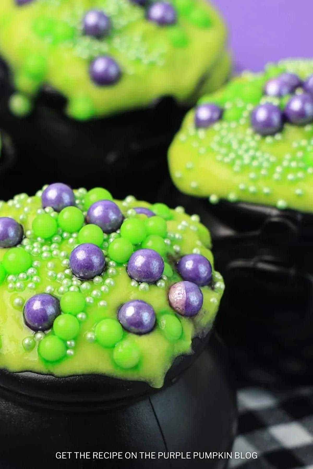 Halloween-themed caldron pudding cups with purple and green sprinkles—perfect for hocus pocus snack ideas.