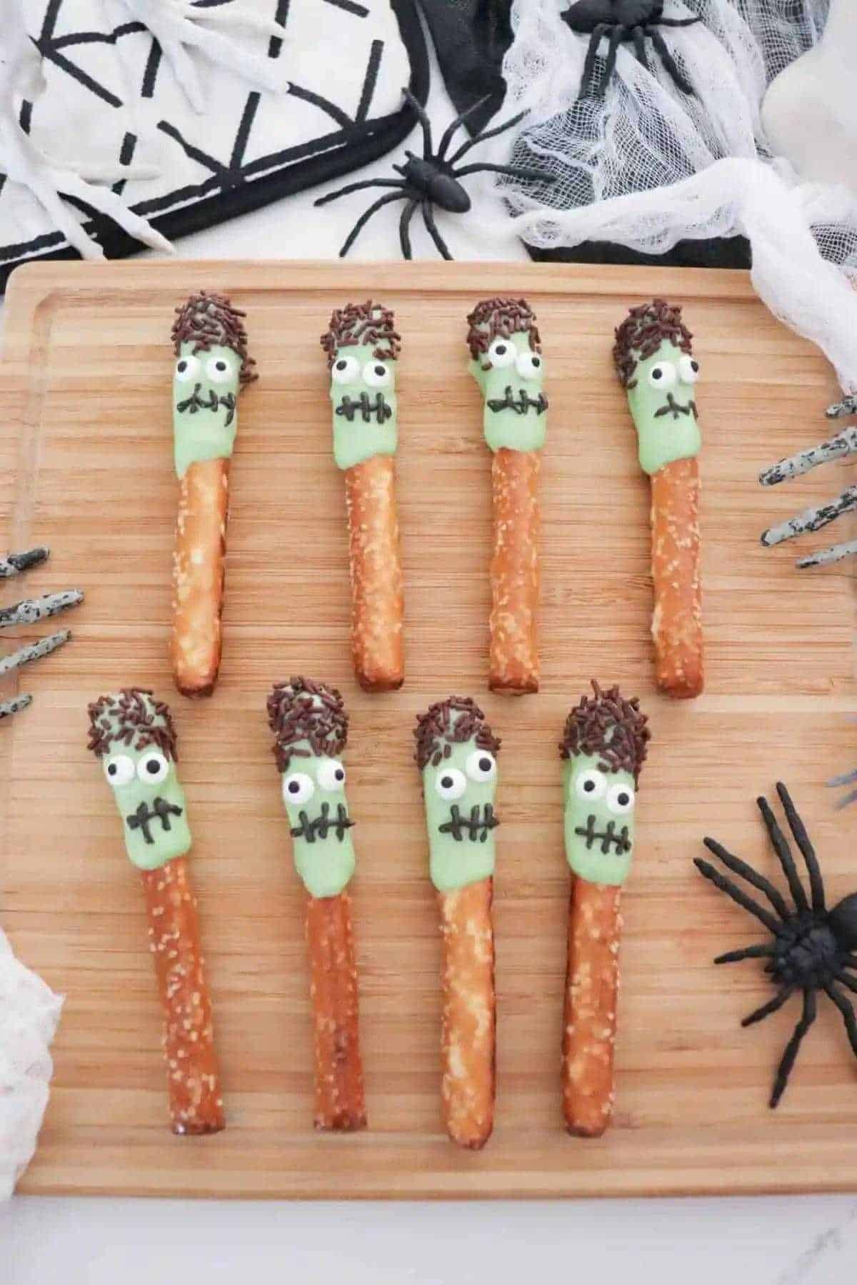 Zombie pretzel sticks presented on a wooden cutting board.