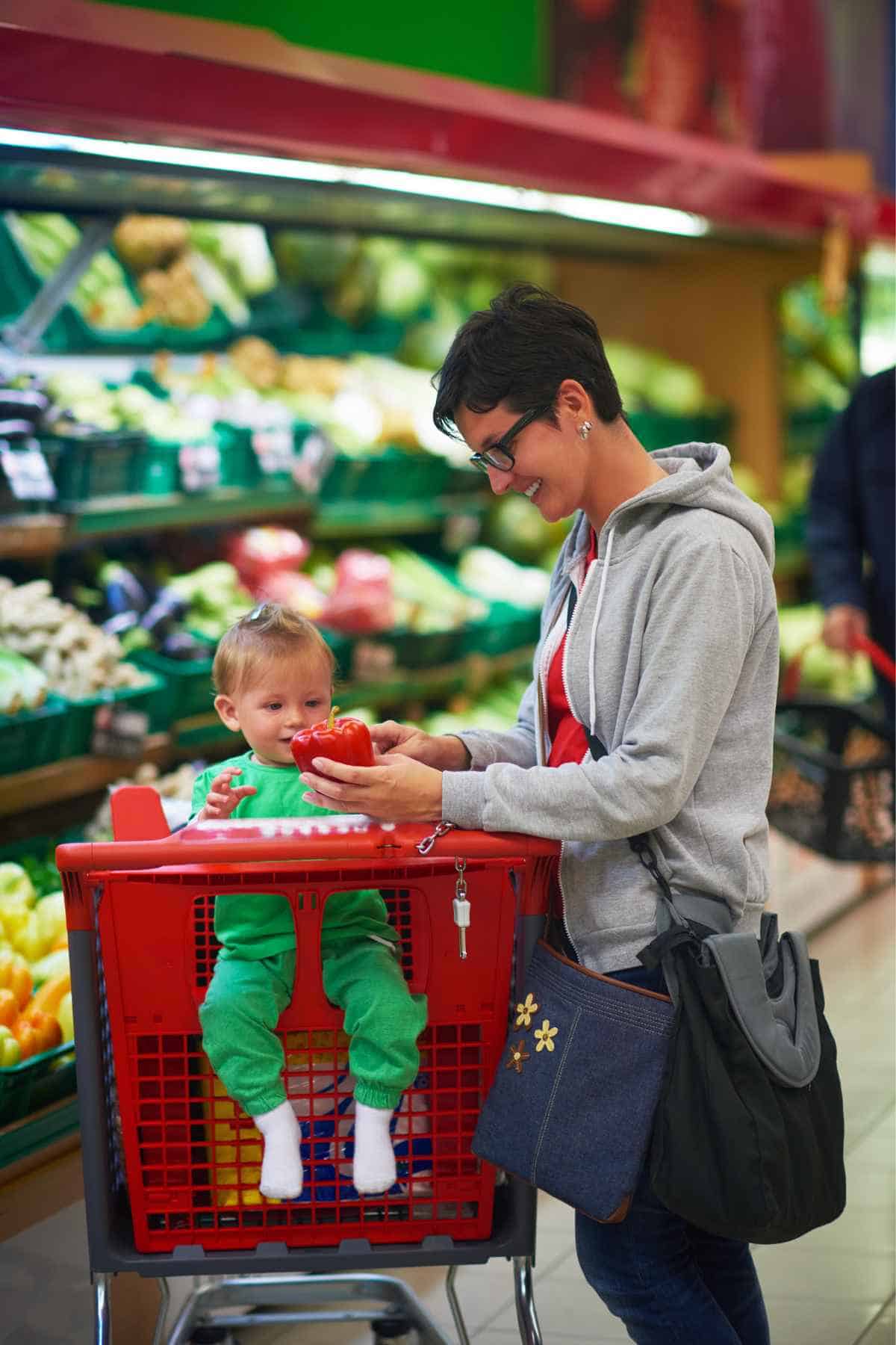 A woman running errands with a toddler in a shopping cart. 