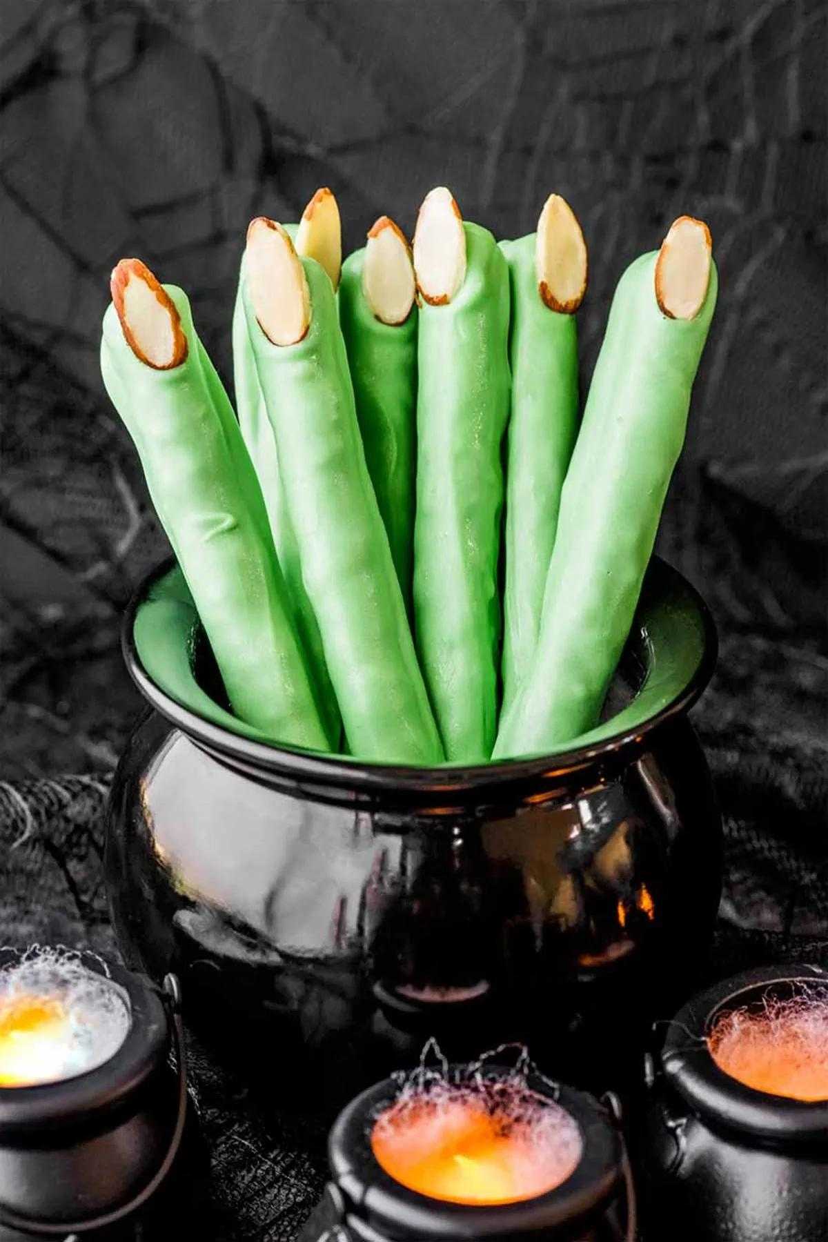 Halloween party snack ideas inspired by Frankenstein's fingers displayed in a spooky black bowl with candles.