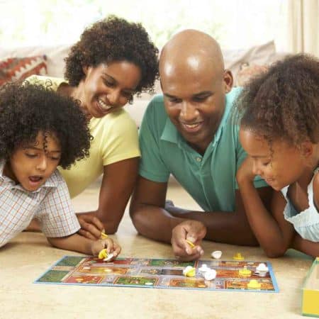 A family of 4 playing a board game on the floor.