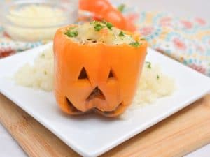 Close up view of a Halloween stuffed pepper served on a white plate.