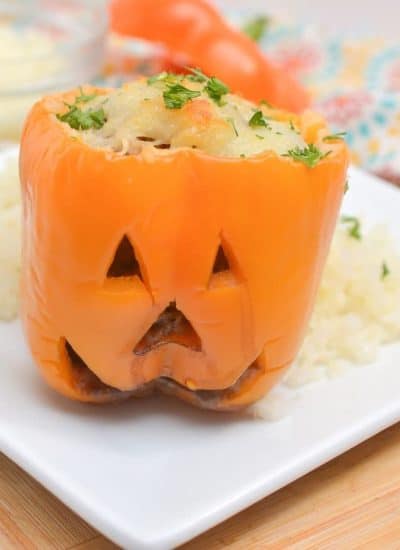 Close up view of a Halloween stuffed pepper served on a white plate.