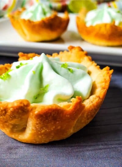 Front view of key lime pie bites. One is on the table and the rest are on the baking sheet