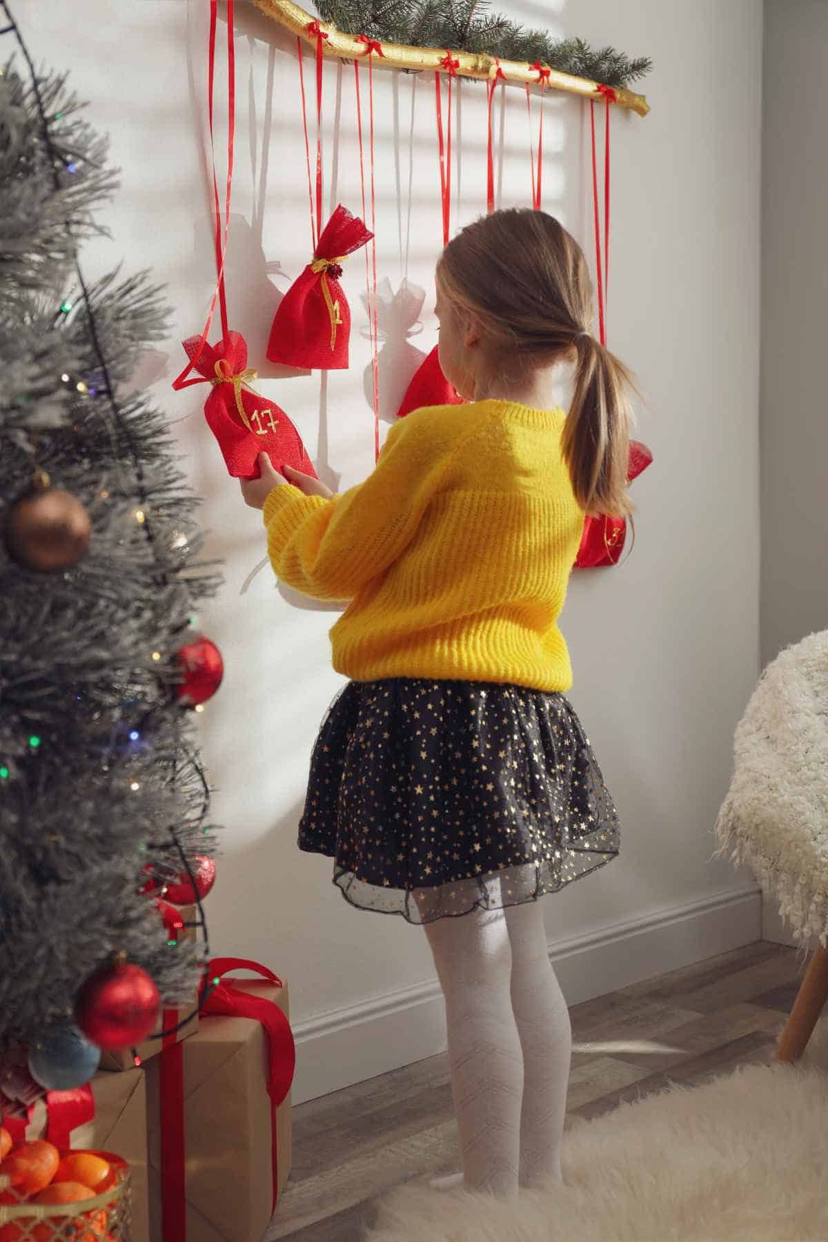 A little girl holding a red festive bag numbered 17 from her Christmas advent calendar.