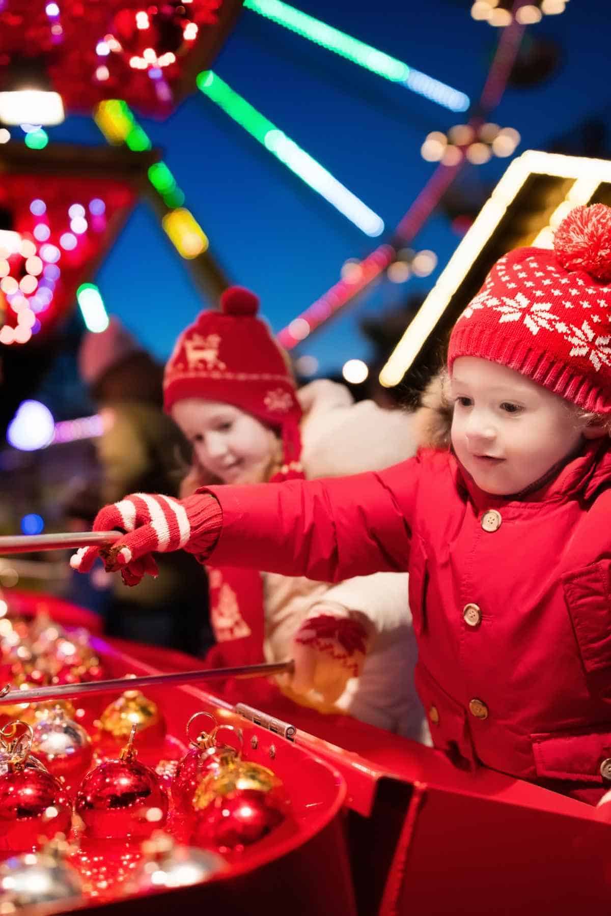 Two children enjoying Christmas activities as they play with ornaments on a ferris wheel.