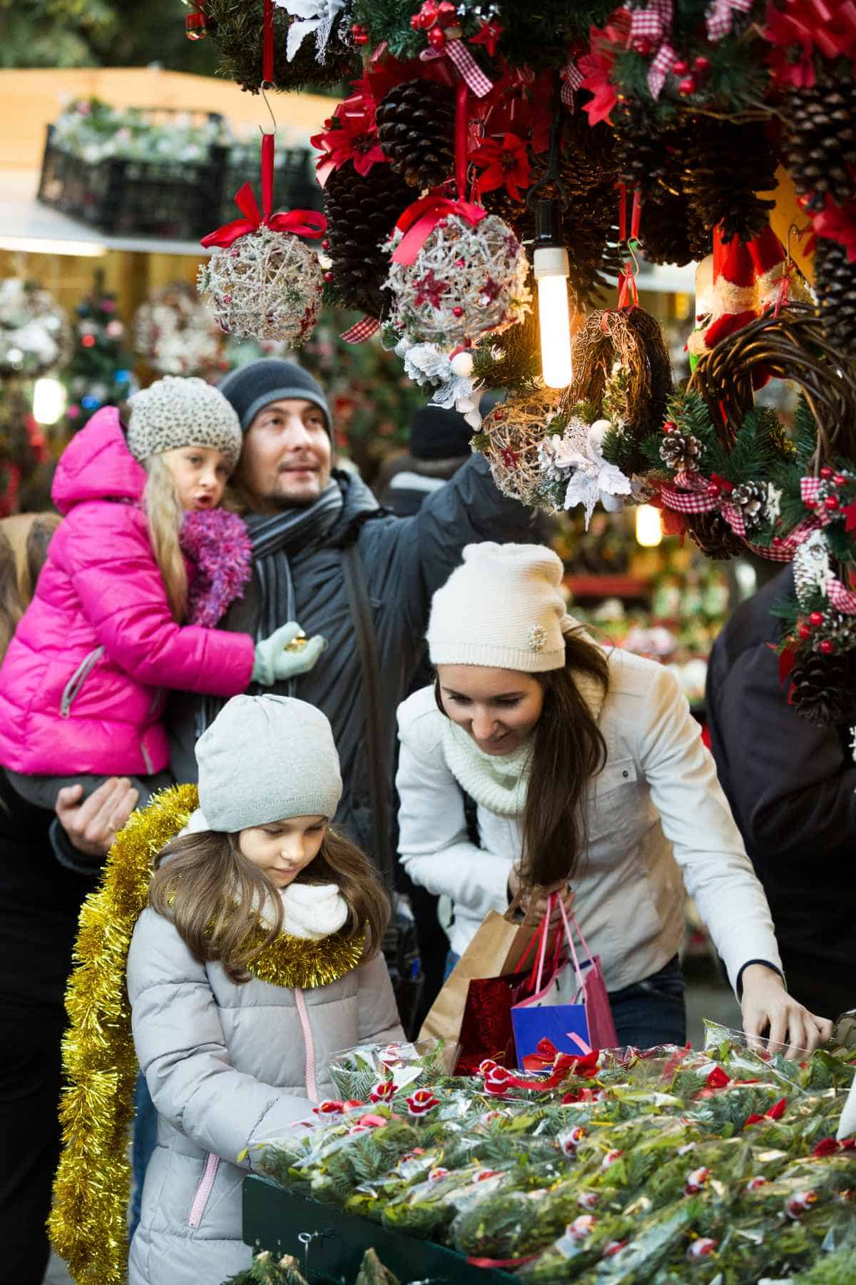 A family of 4 is engaging in fun Christmas activities at a festive market.