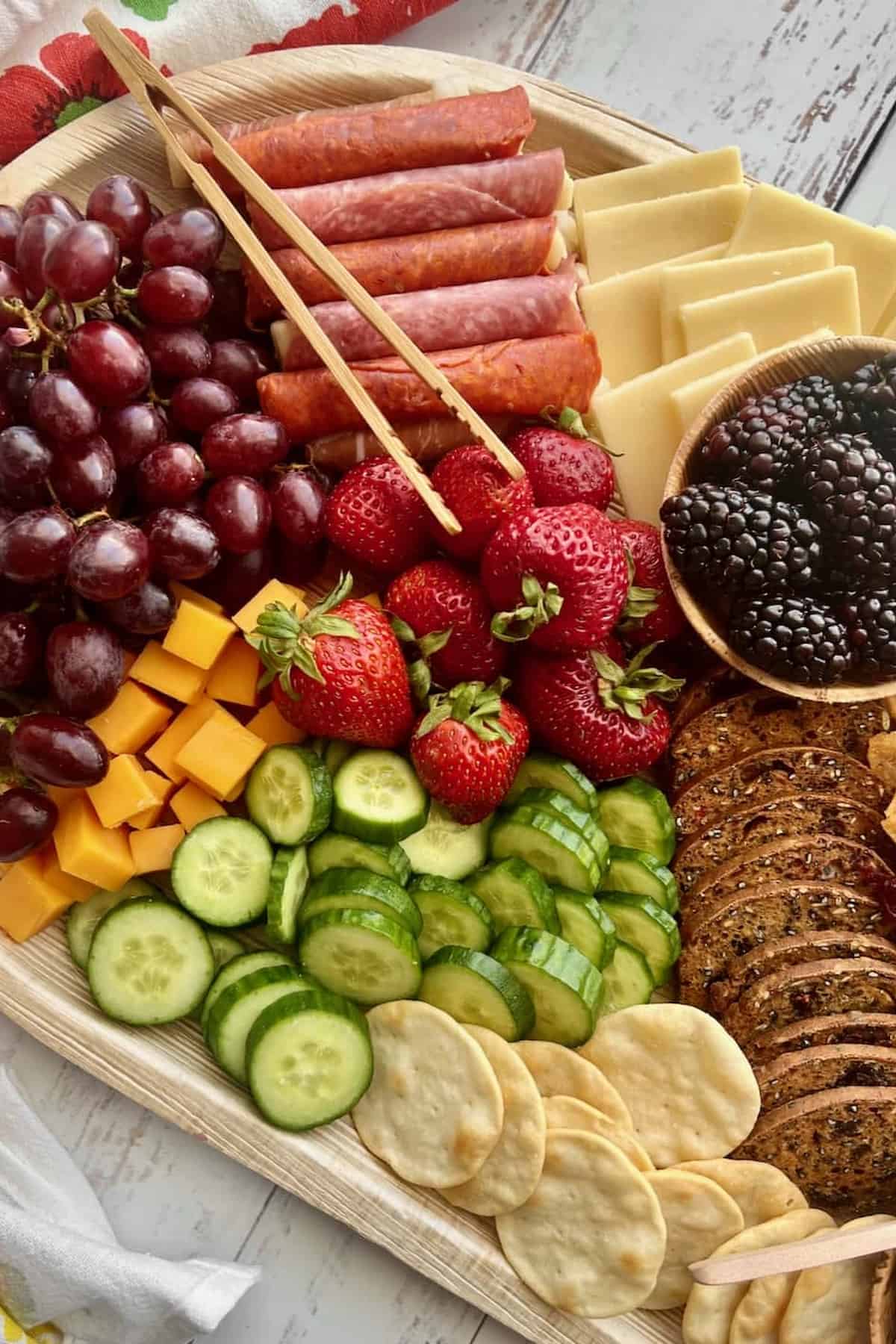 A tray of fruits, cheese, crackers and meat.