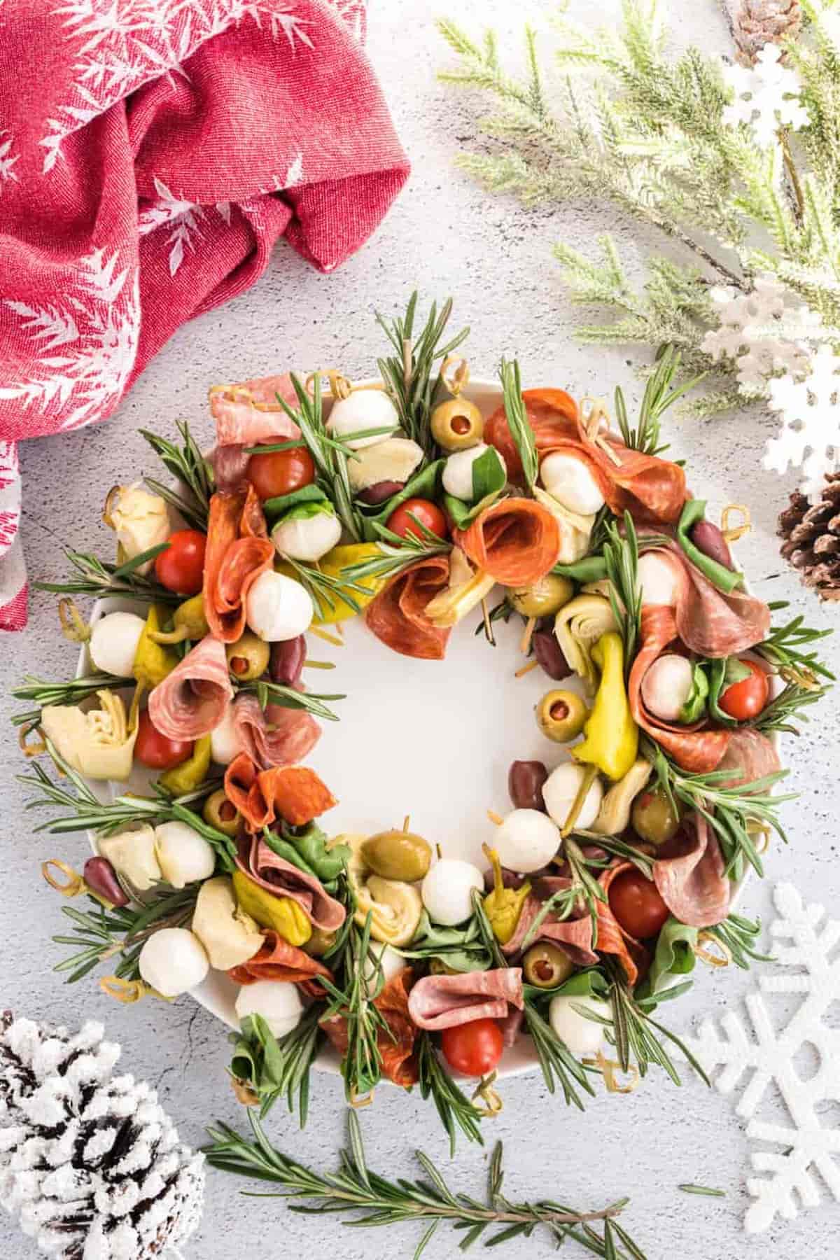 A Christmas wreath made out of ham, cheese, and fruits.