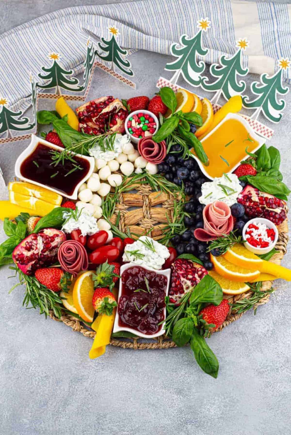 A Christmas platter with fruit and cheese on it.