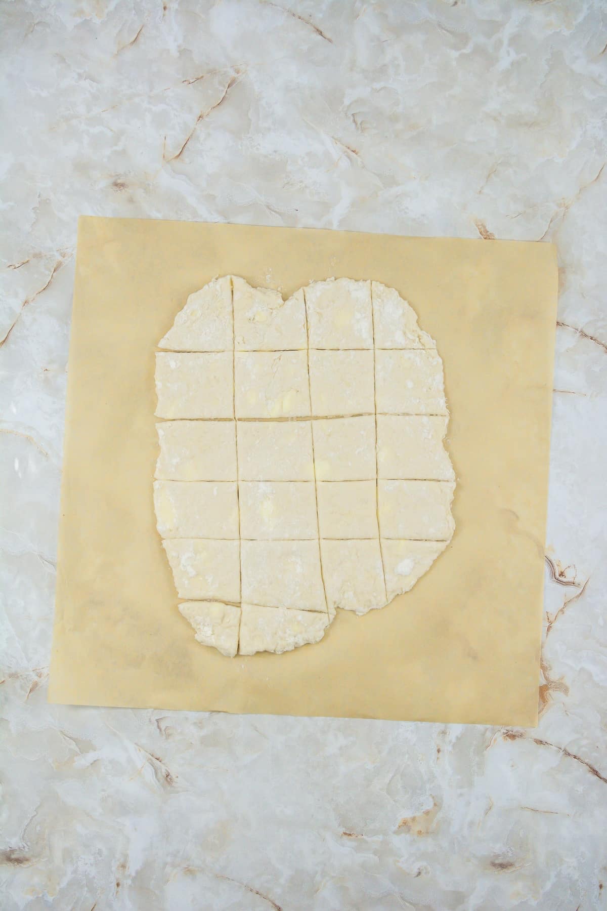 Dough rolled out and cut into squares on a piece of parchment.