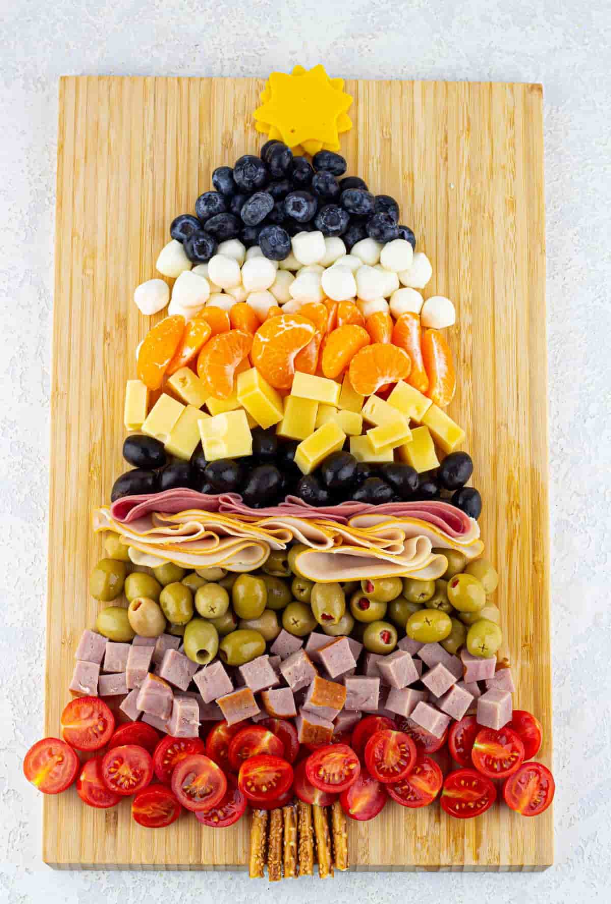 A Christmas tree charcuterie board made of cheeses, meats, and fruits.