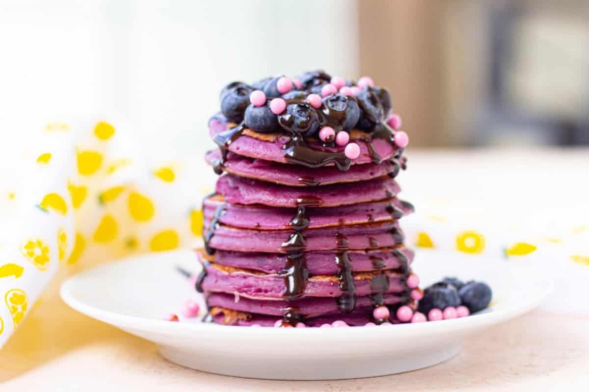 A stack of purple pancakes on a plate.