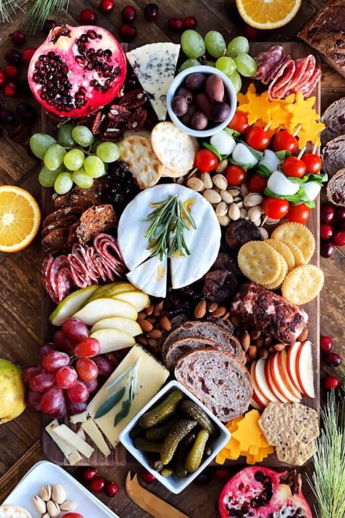 A board with a variety of meats, cheeses, fruits, and bread.