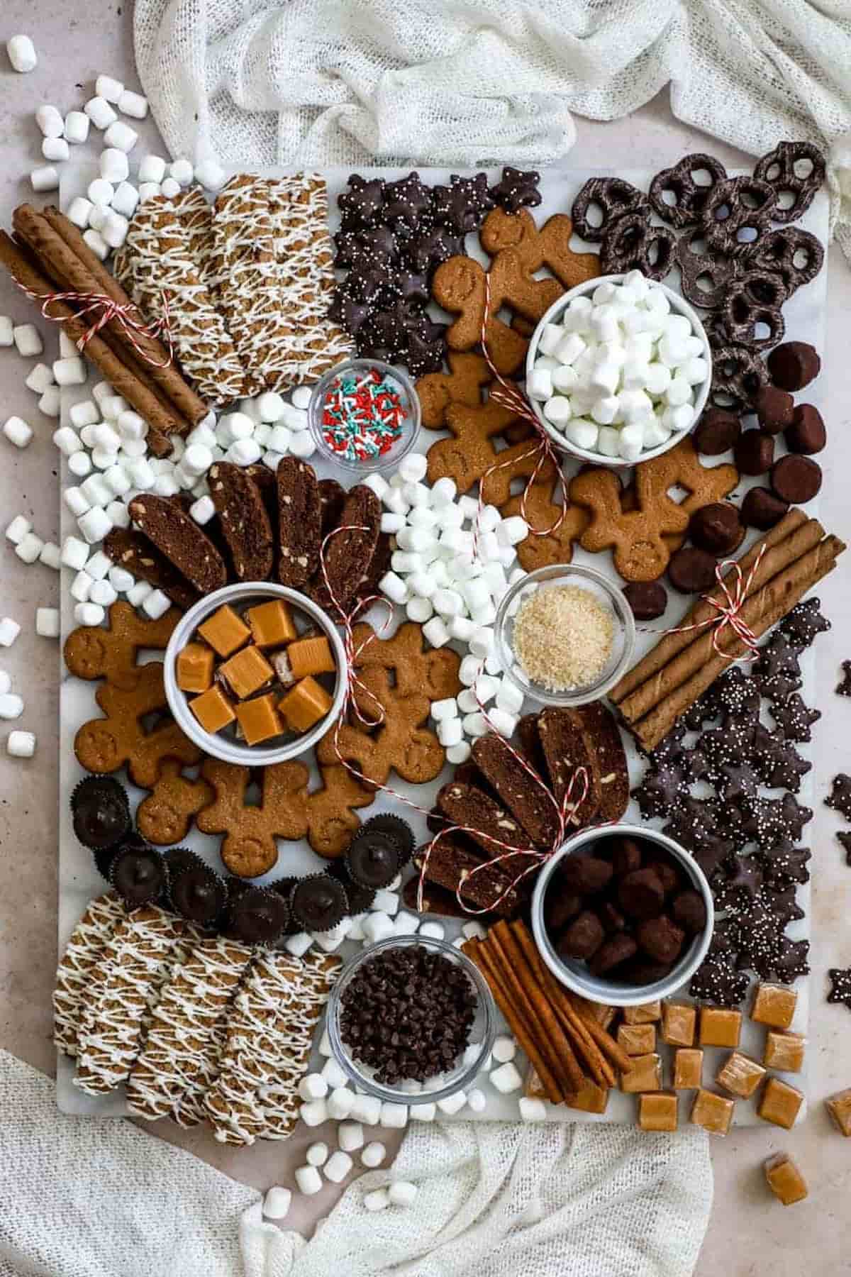 A tray of chocolates, marshmallows, and cookies on a table.