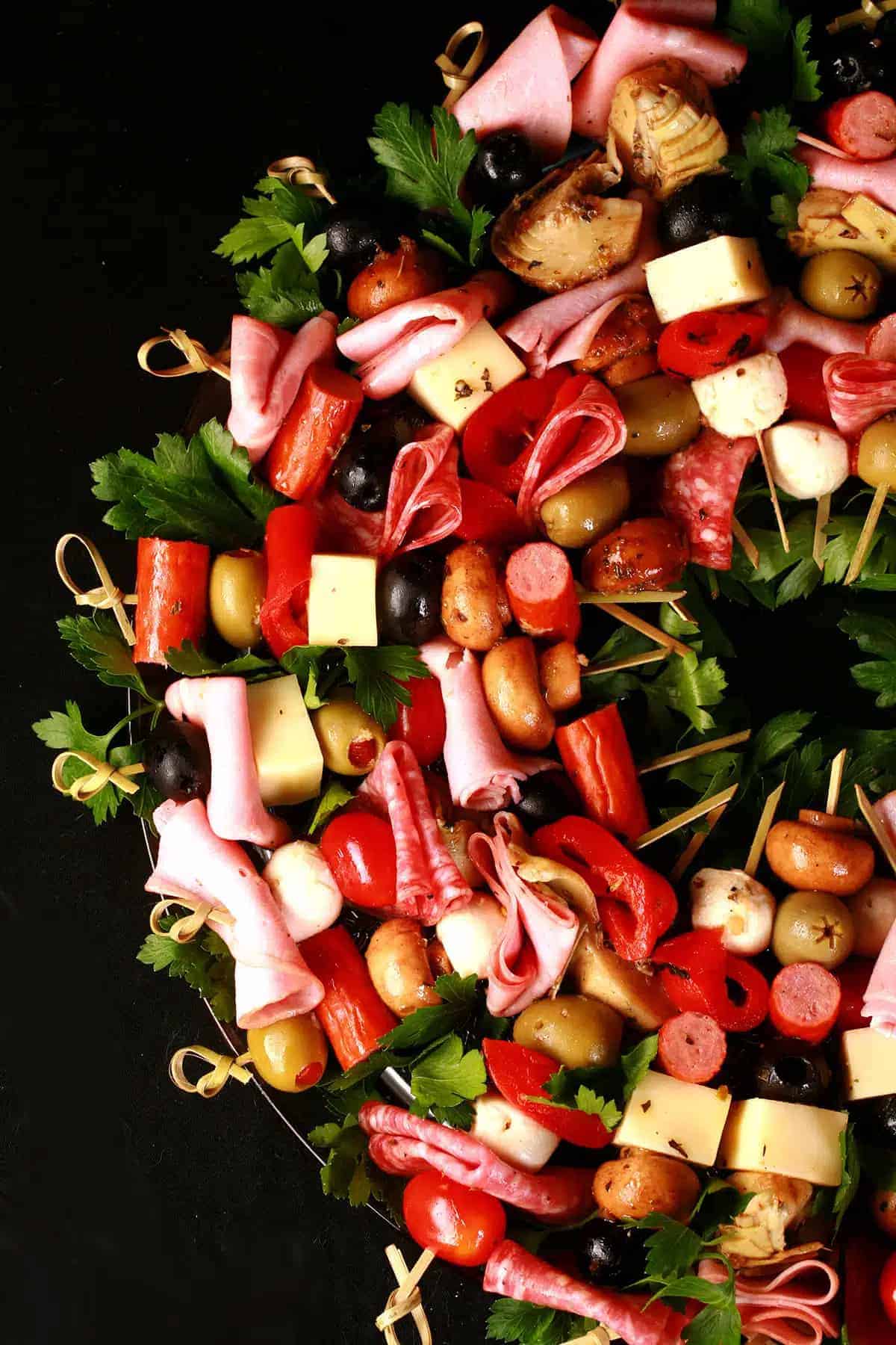 A Christmas wreath made out of meats, cheese, and fruits on skewers.