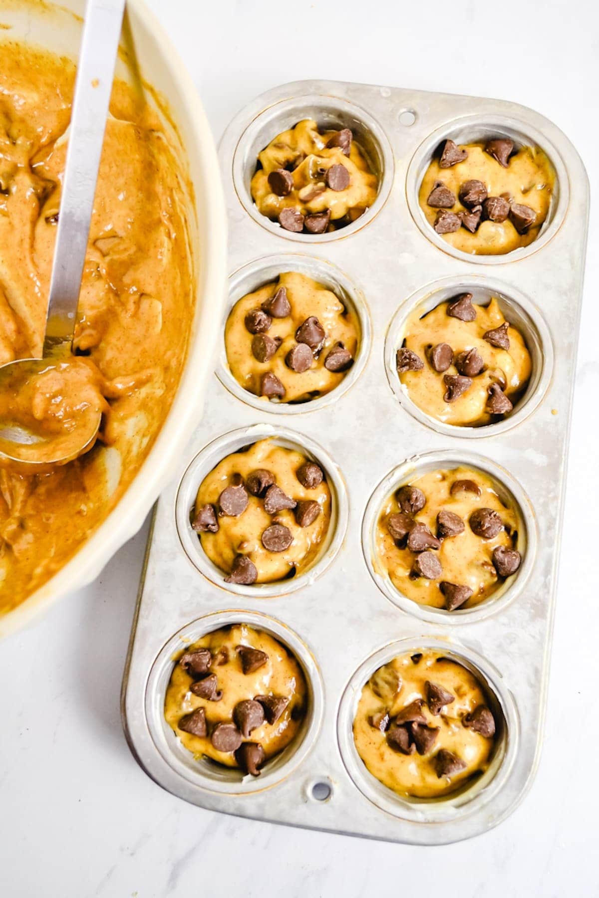 Chocolate chip muffin batter in a muffin tin.