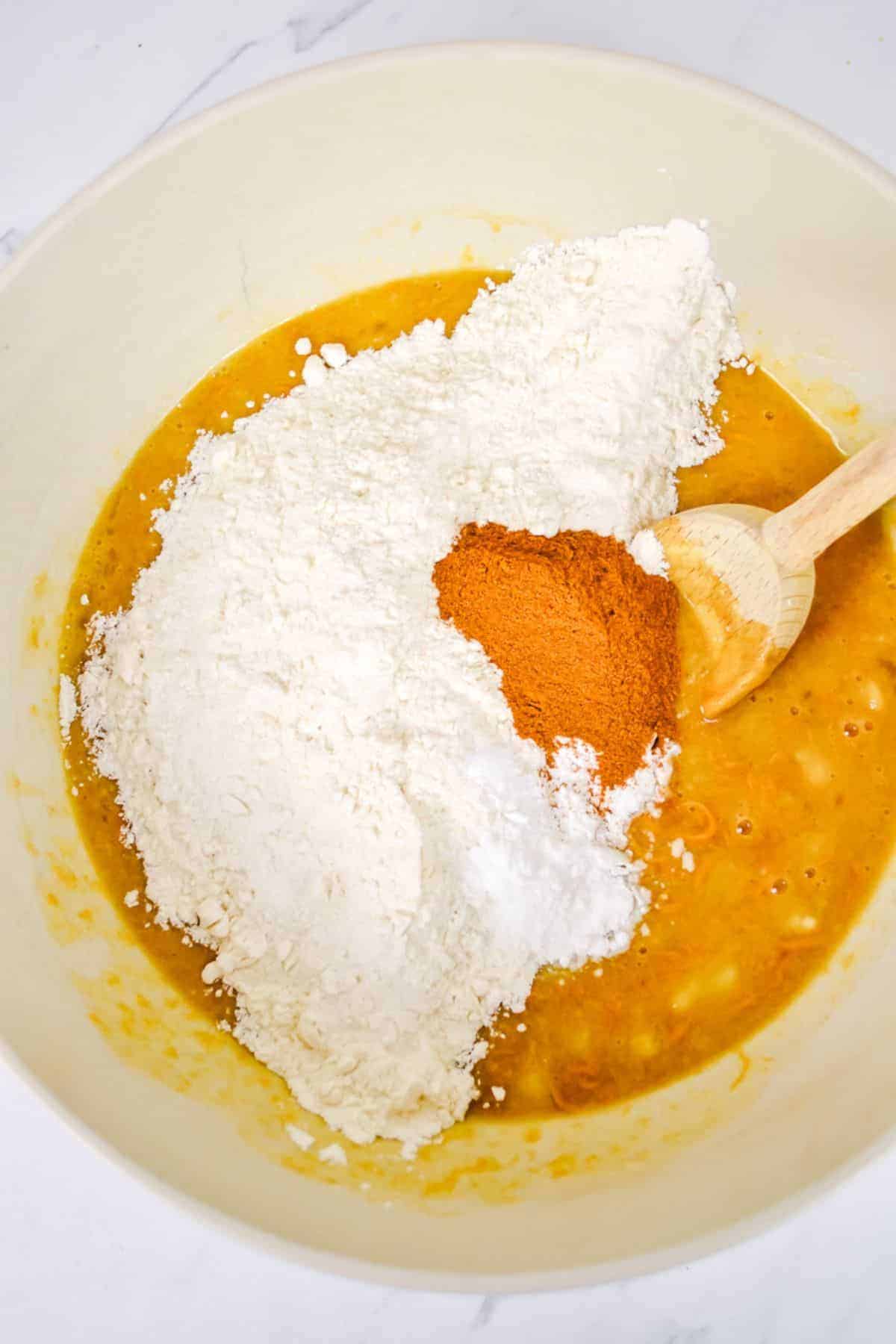 A bowl of flour and spices with a wooden spoon.