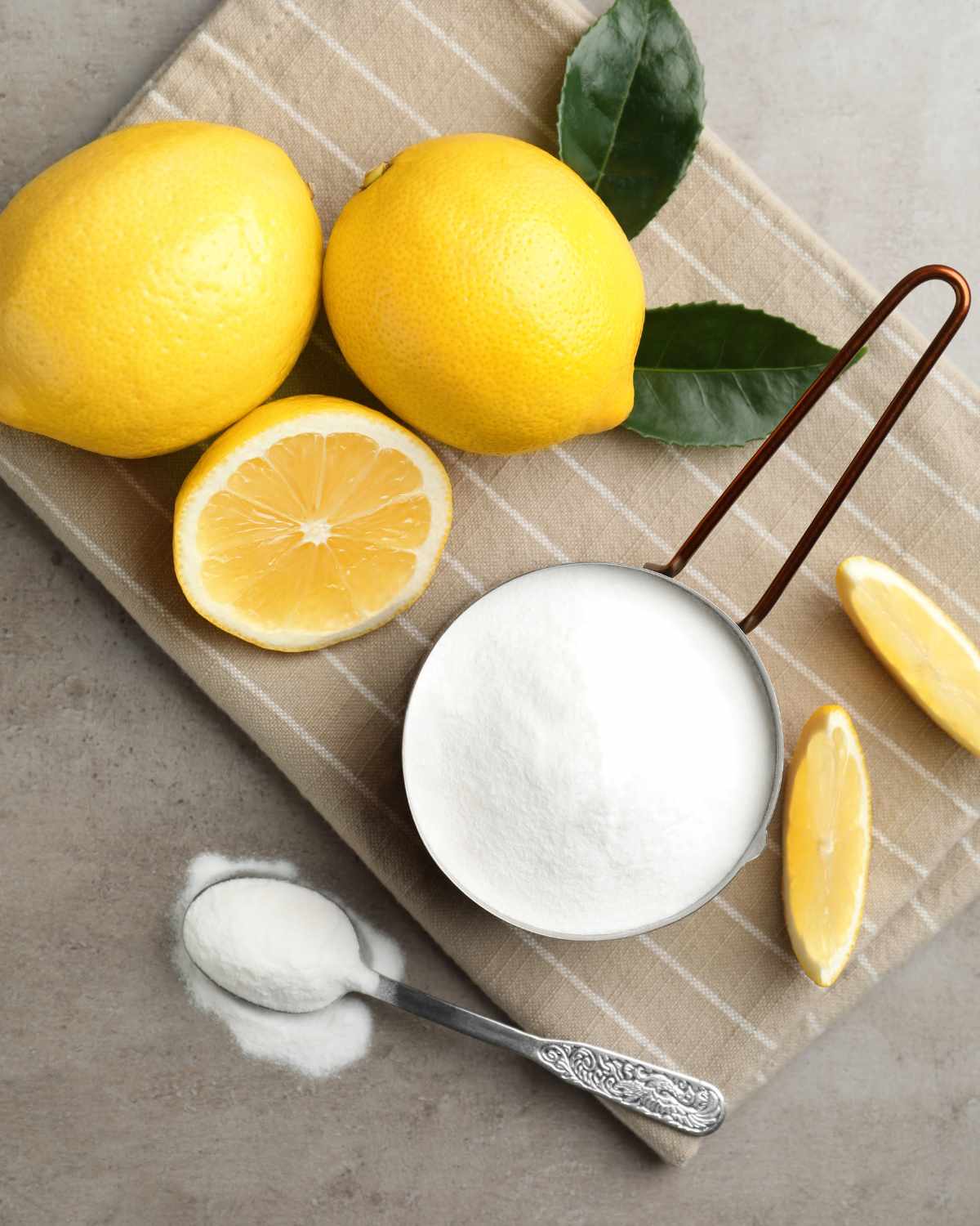 Lemons, baking powder, and a spoon on a cloth.