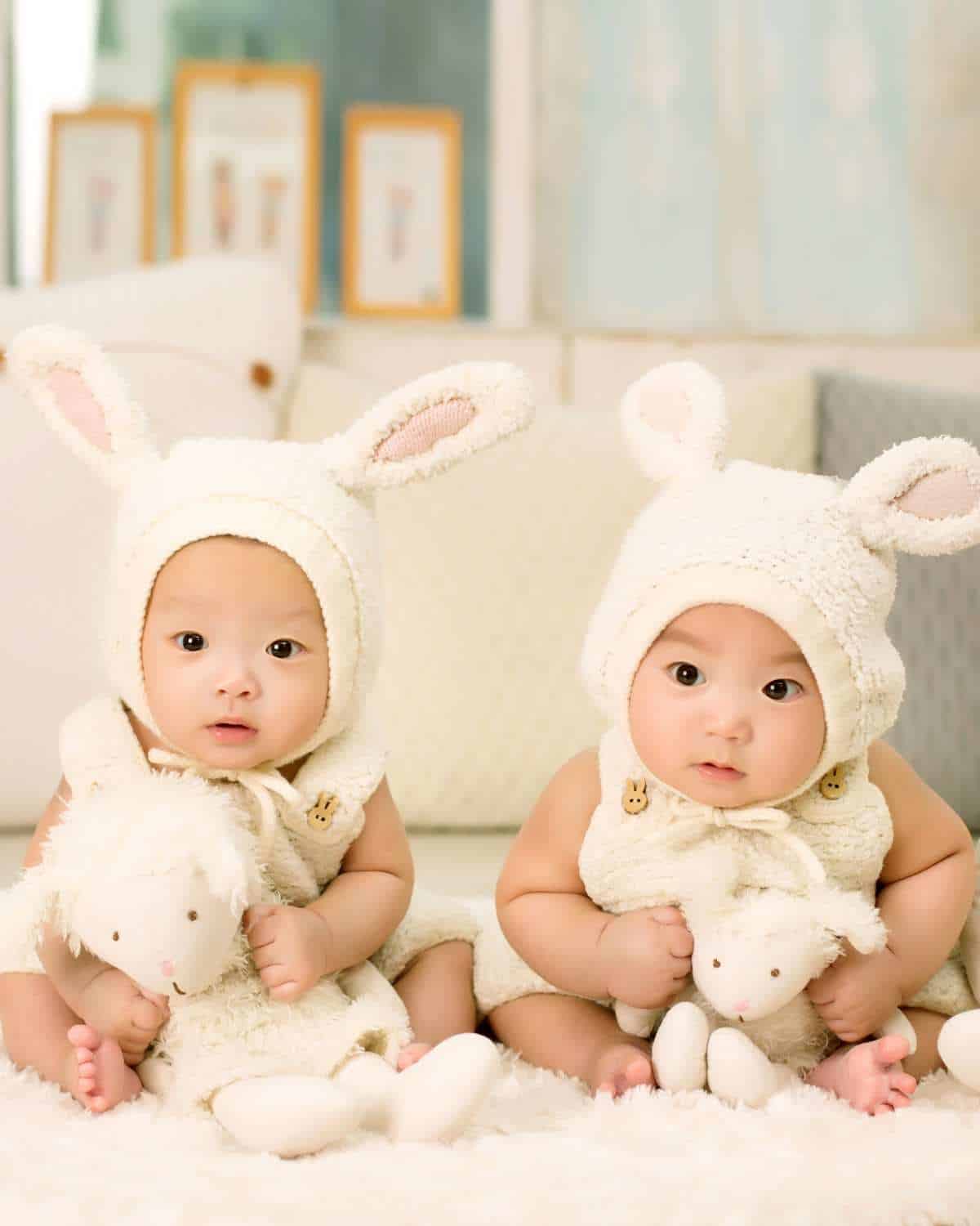 Two babies wearing bunny-themed outfits.