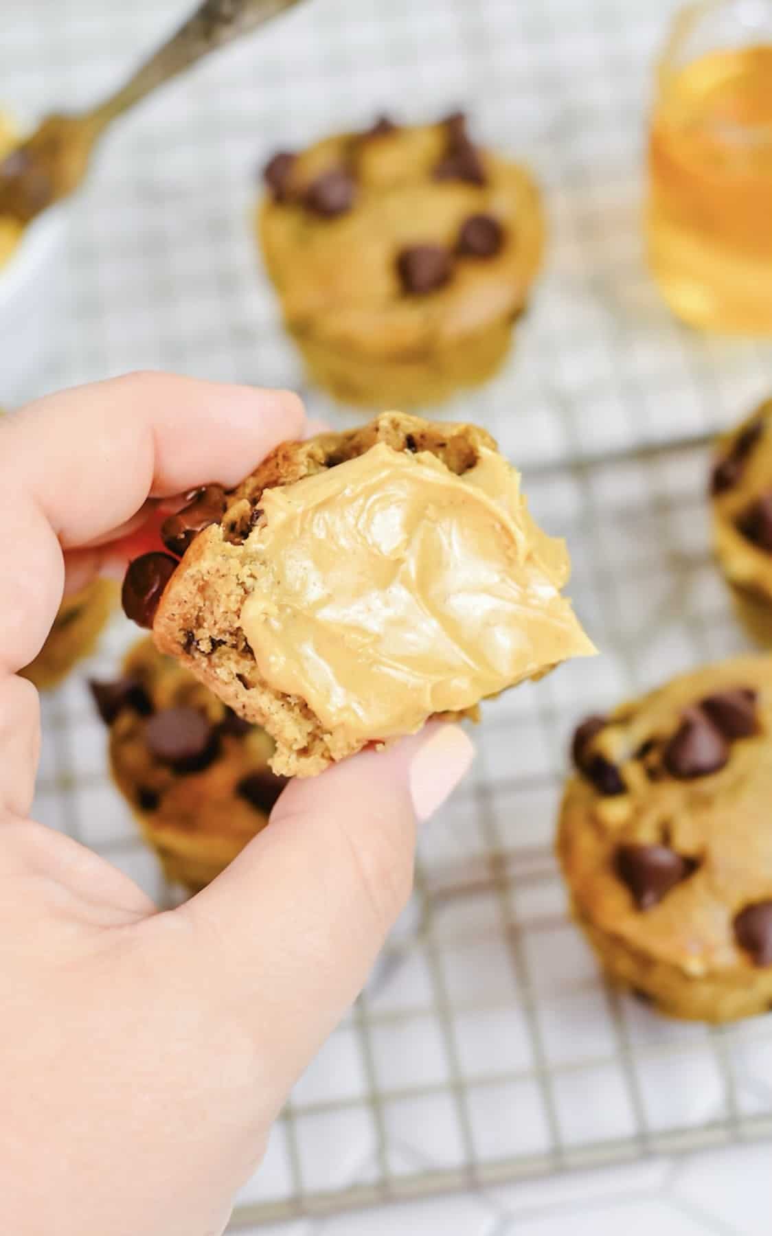 A person holding a muffin dipped in peanut butter.