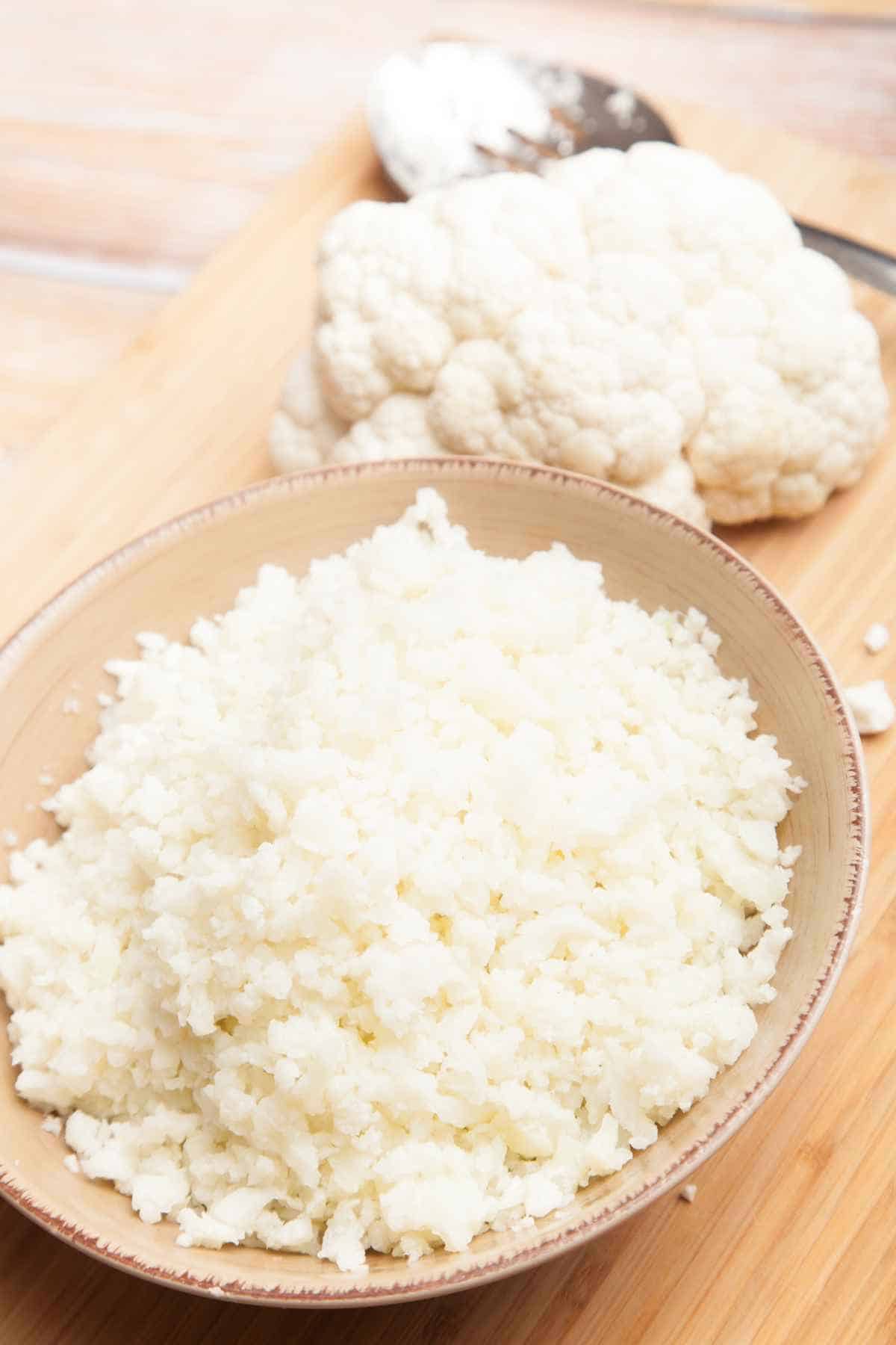 Cauliflower rice in a bowl next to a spoon.