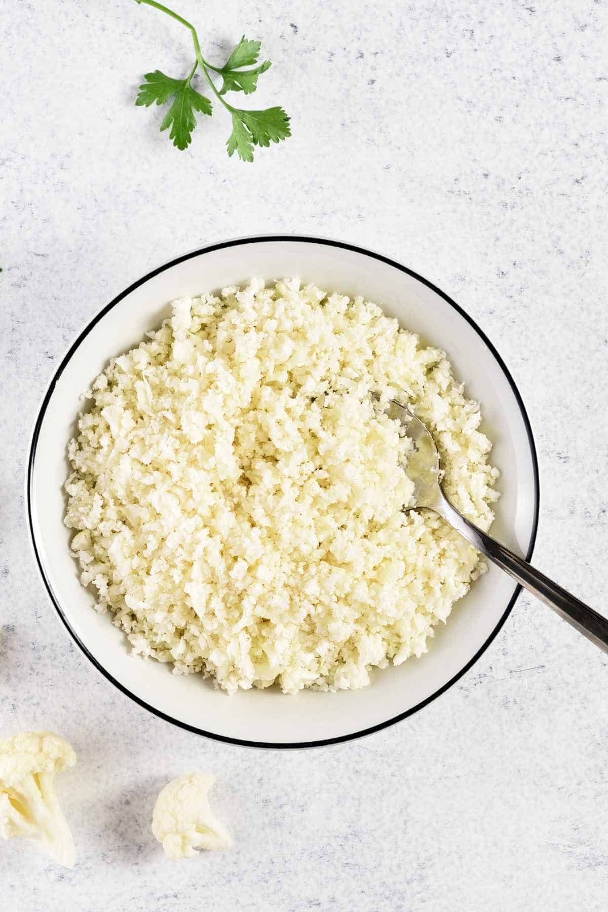 Cauliflower rice in a bowl with a spoon.