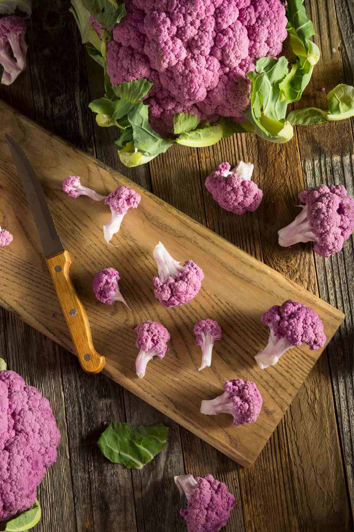 Purple cauliflower on a cutting board with a knife, perfect for preparing cauliflower rice.