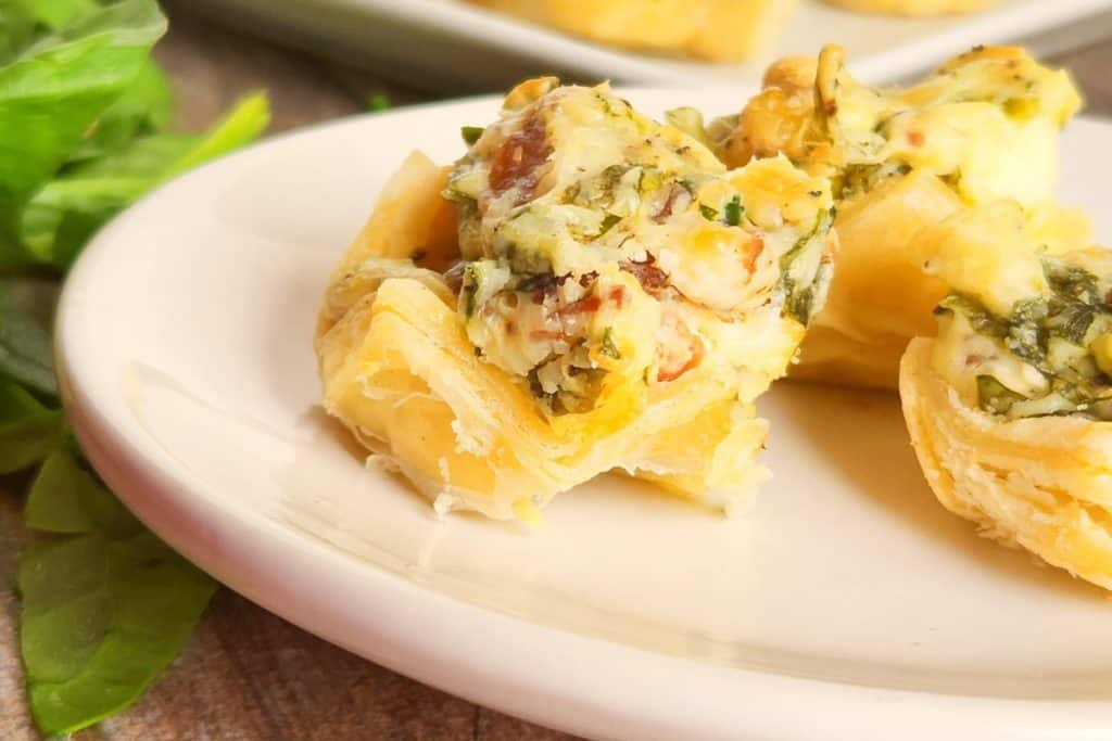 A plate of mini cheese and spinach tartlets.