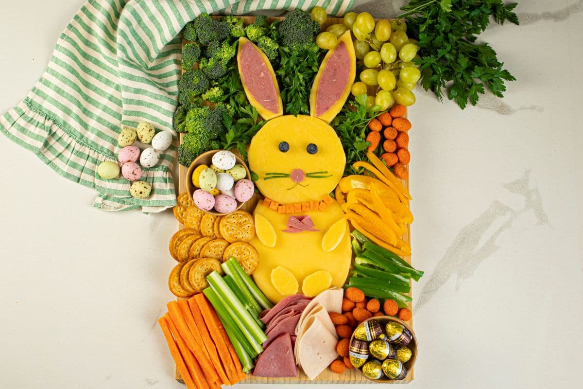 An Easter bunny charcuterie board made with cheeses, meats, chocolates, fruits, and vegetables.