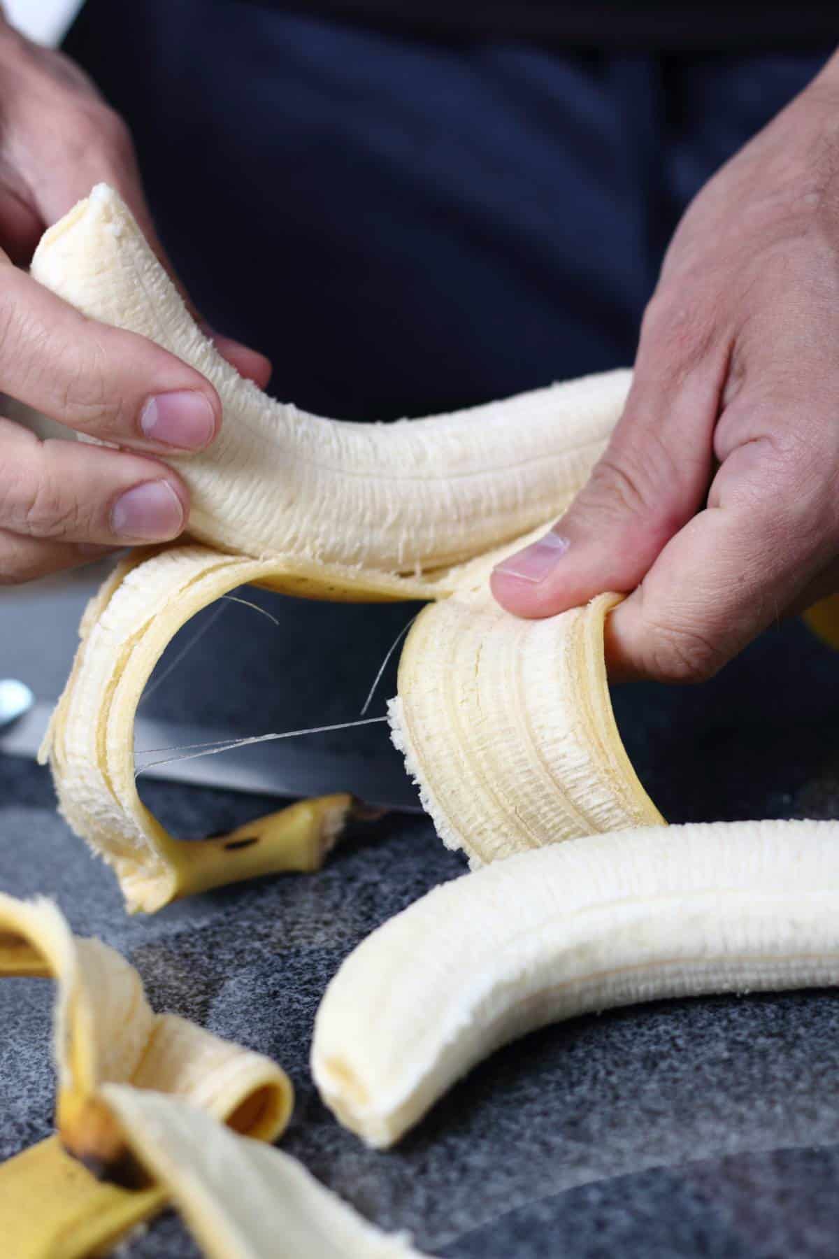 A person peeling yellow bananas.