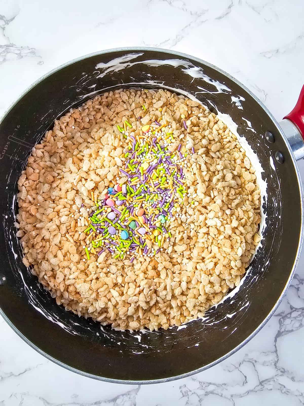 A pan with rice cereal treat mixture with colorful sprinkles on top.