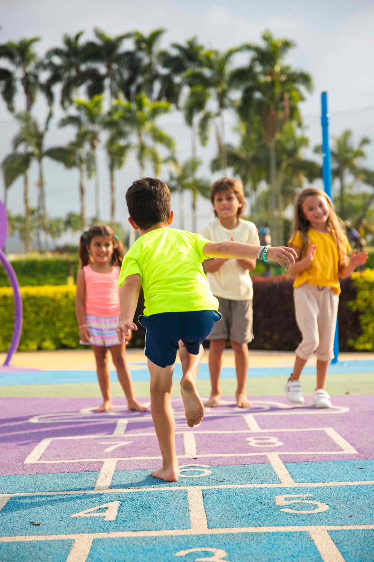 Children playing hopscotch outdoors on a sunny day.