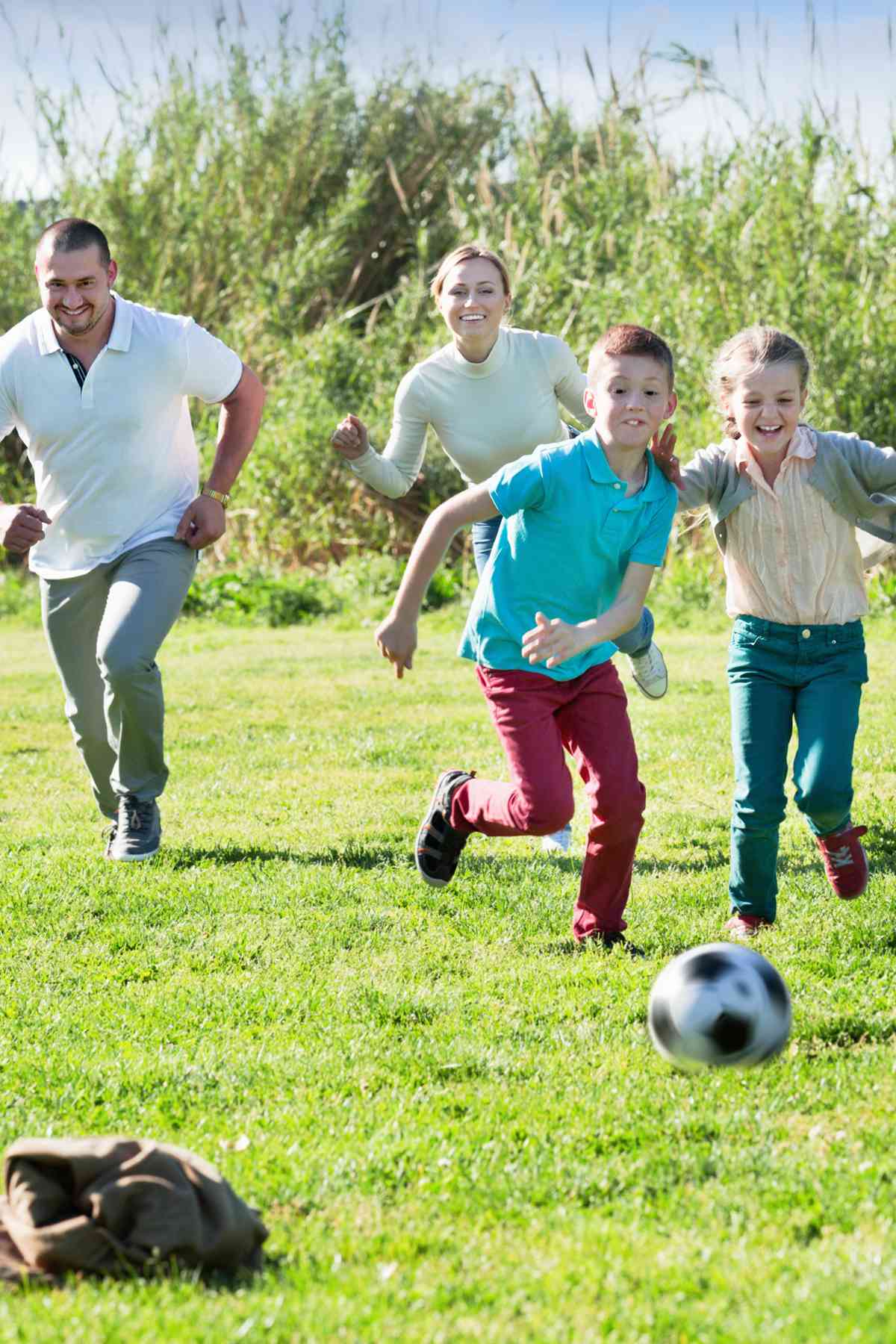 Family playing soccer together on a grass field.