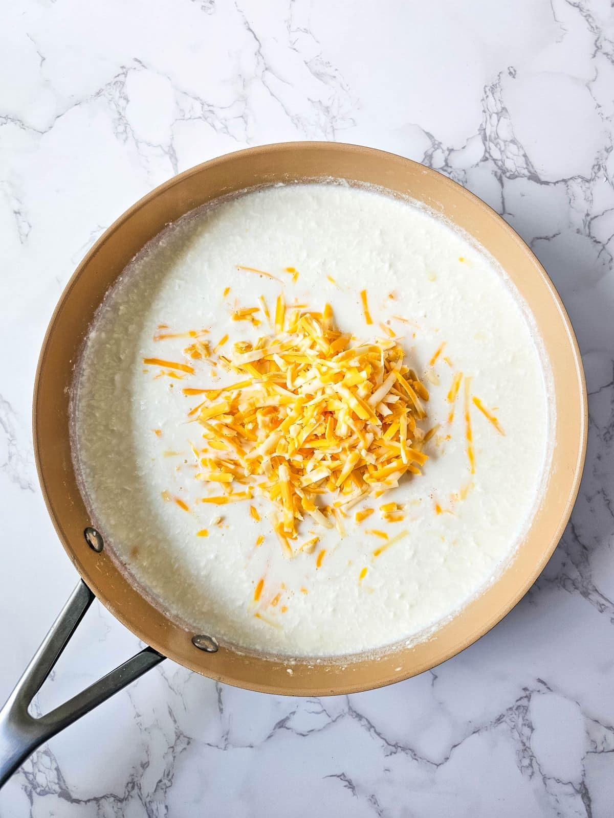 A pan of cream cheese mixture with shredded cheese.