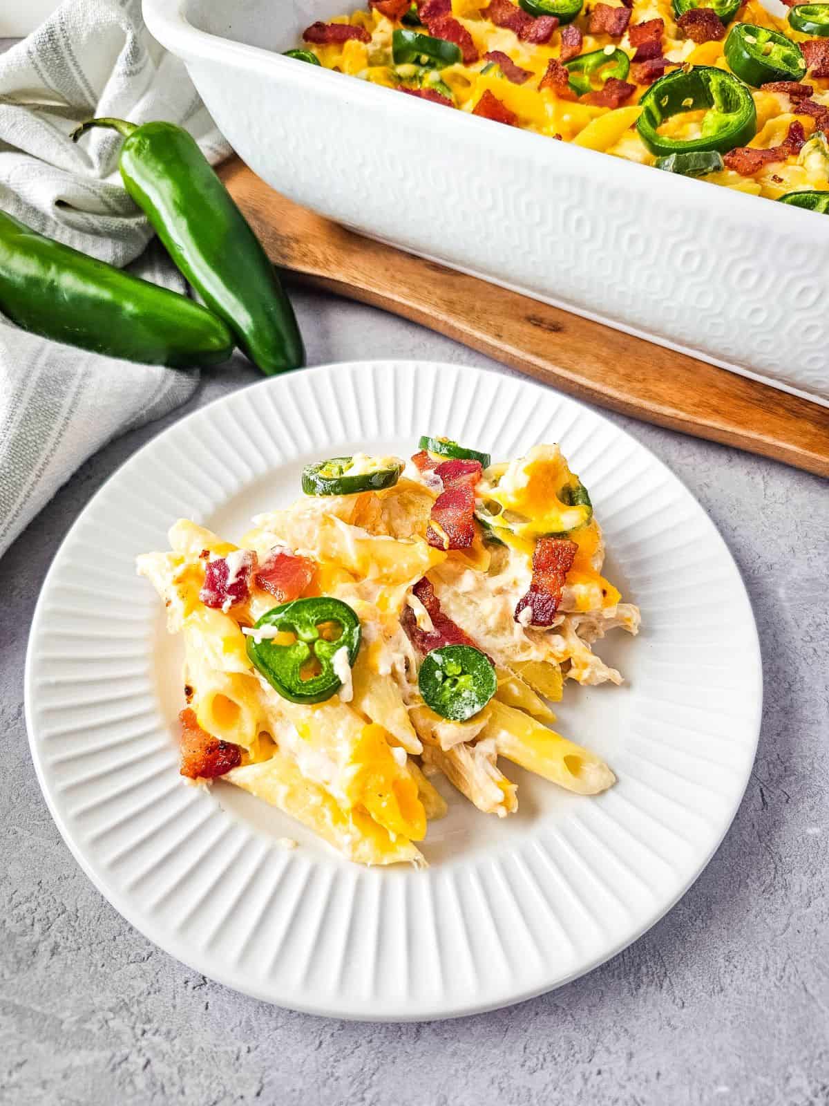 A serving of baked jalapeño poppers chicken casserole topped with bacon bits and sliced jalapeños.