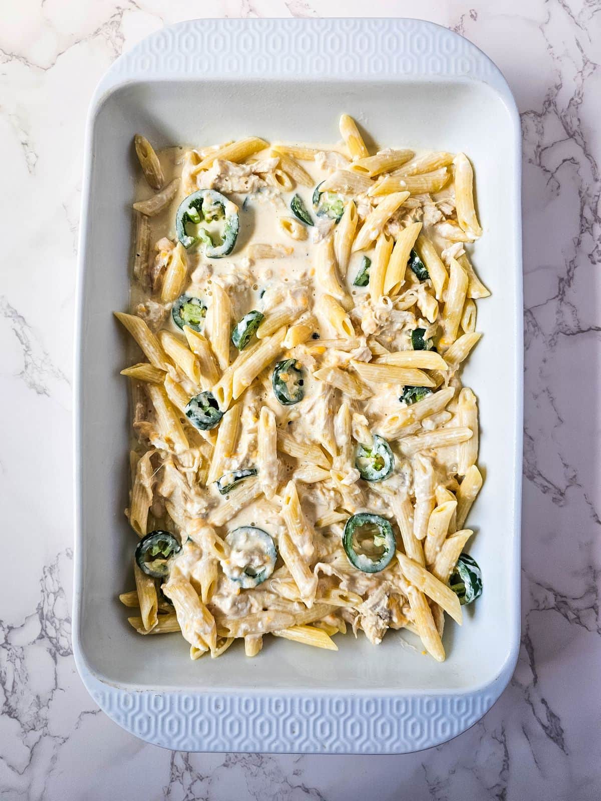 Jalapeño poppers chicken in a casserole dish with cream cheese mixture.