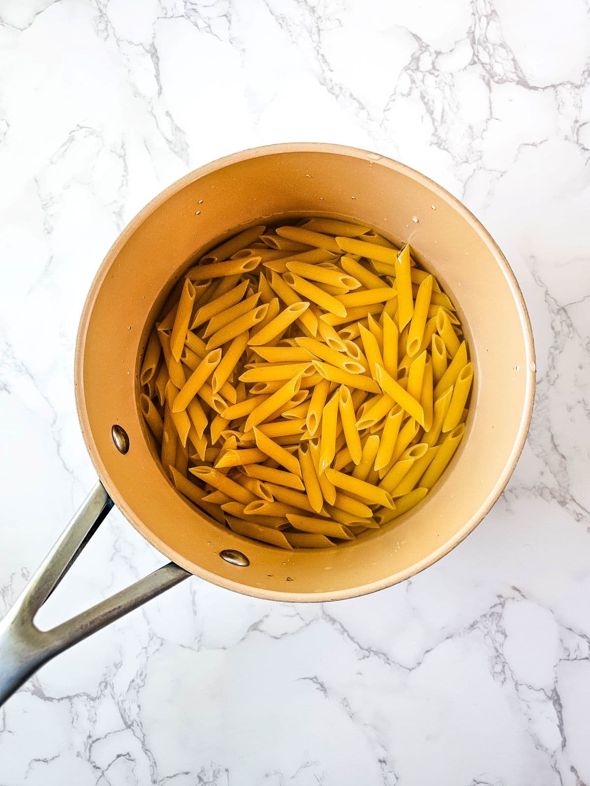 Uncooked penne pasta in a large pot.