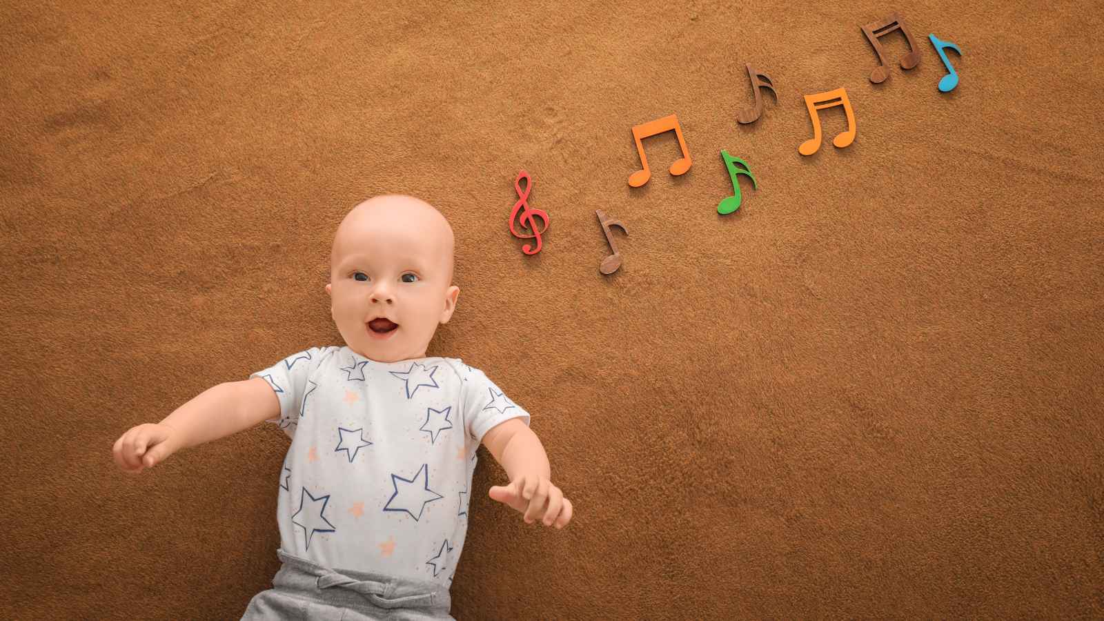 A baby in a star-patterned onesie lies on a brown surface with colorful musical notes arranged beside him.