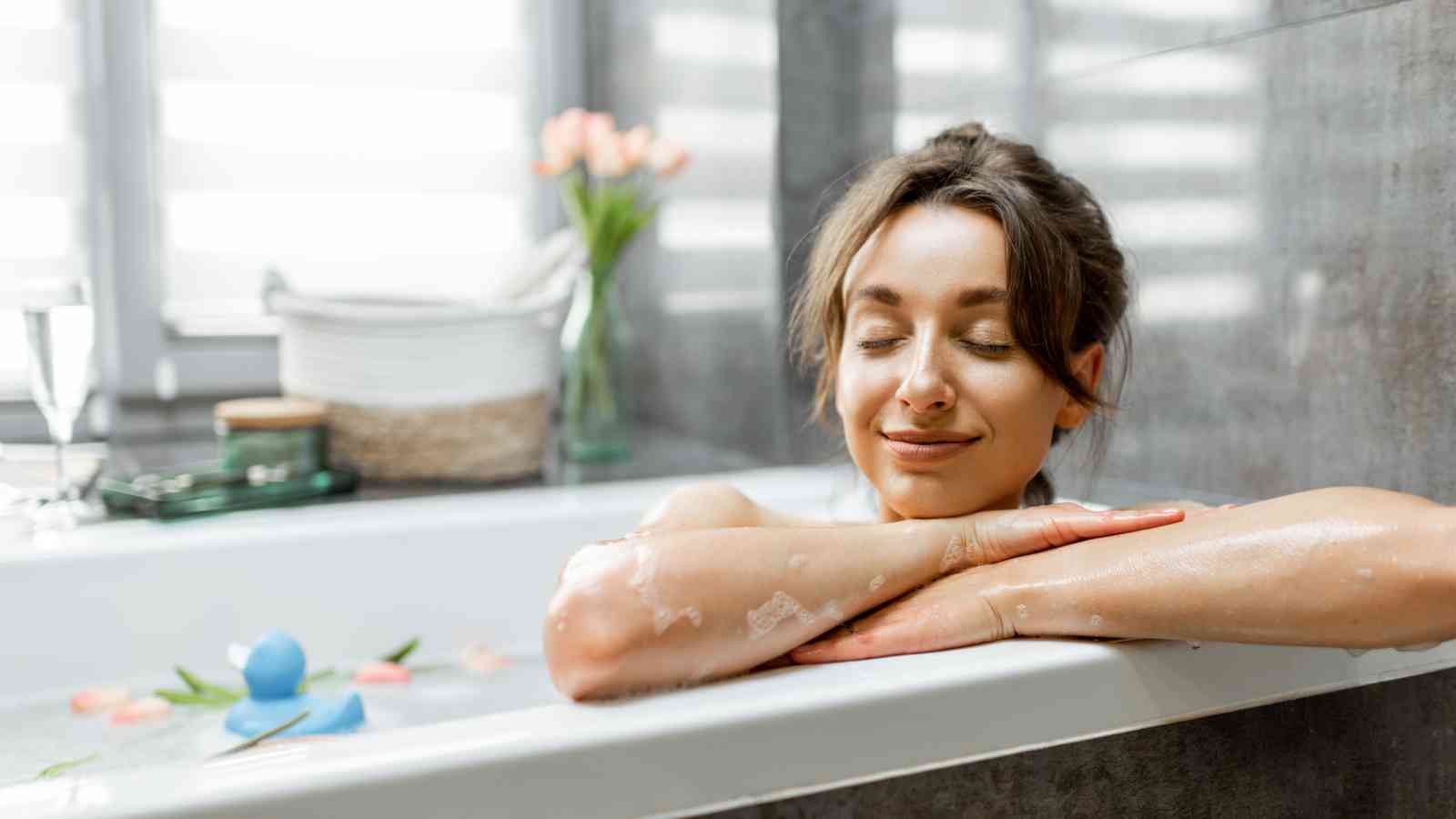 Woman relaxing in a bathtub with her eyes closed, arms resting on the edge.