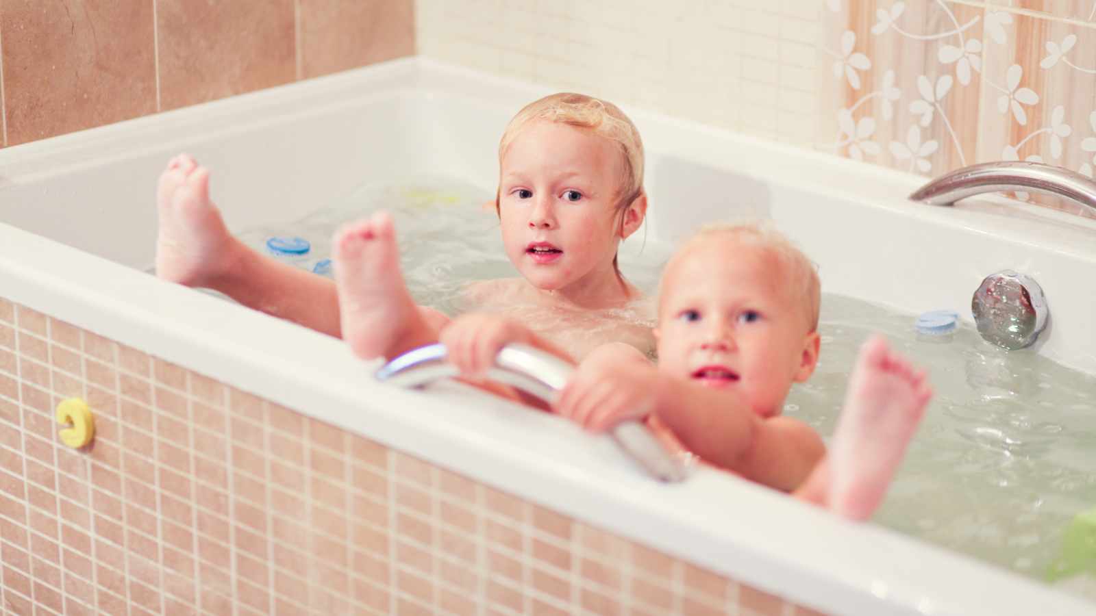Two young children are sitting in a bathtub.