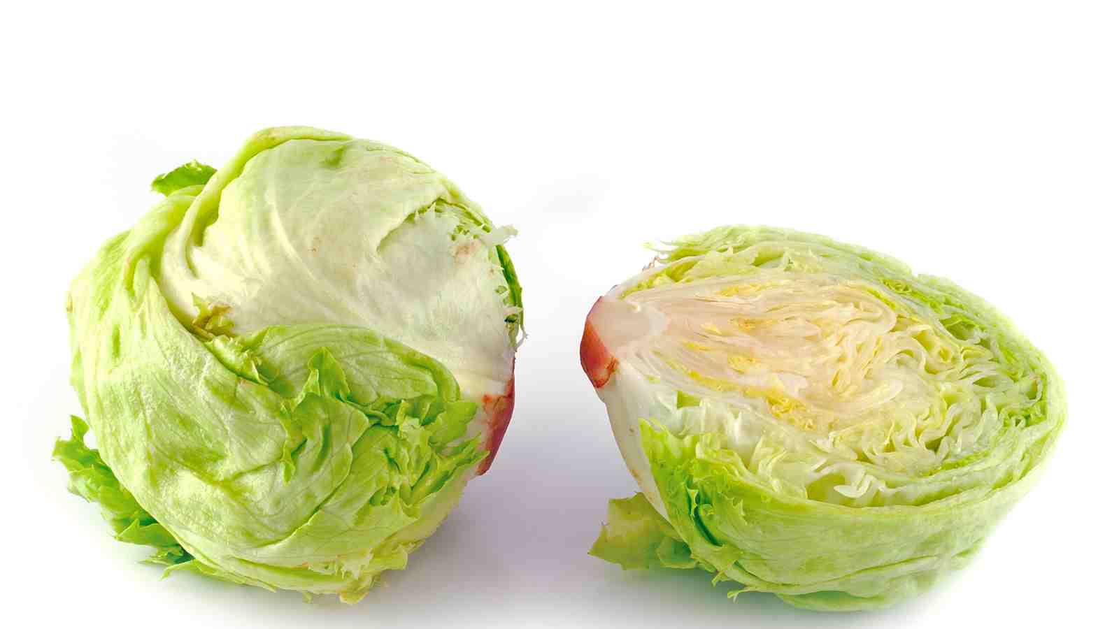 A head of iceberg lettuce cut in half, showing the outer leaves and tightly packed, crisp interior on a white background.