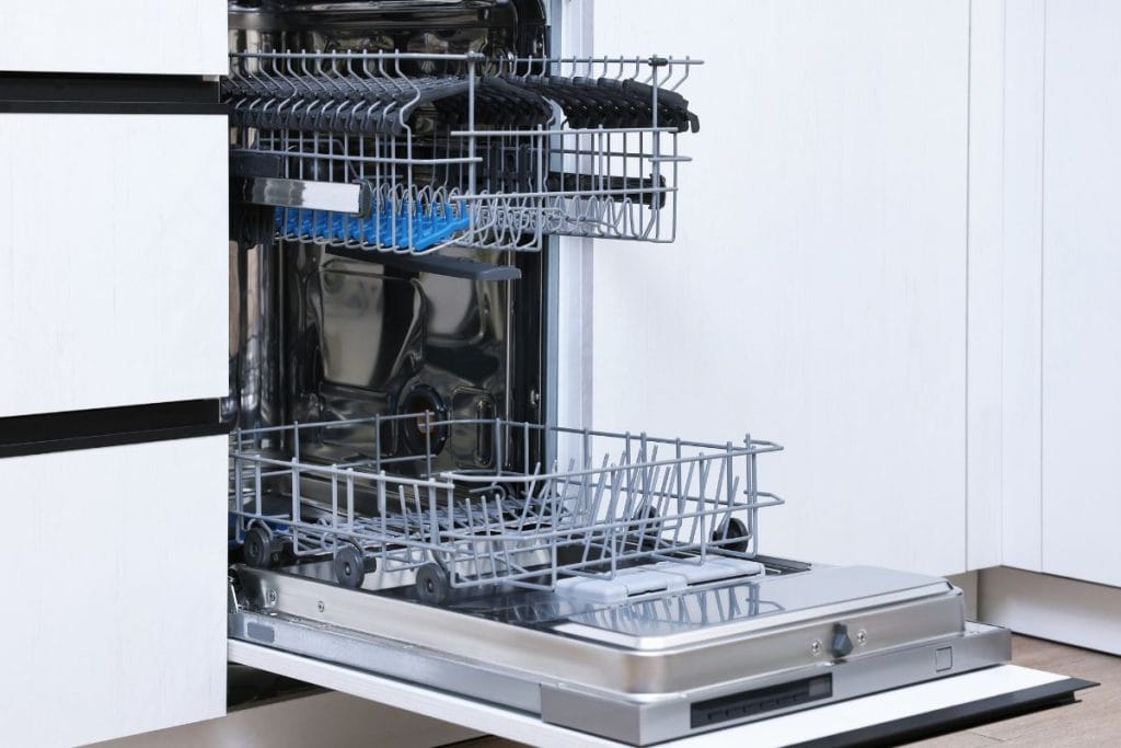 A partially open dishwasher with two empty racks is shown, revealing a stainless steel interior and a detergent compartment on the open door. For optimal results, try cleaning the dishwasher with vinegar to maintain its shine and efficiency.