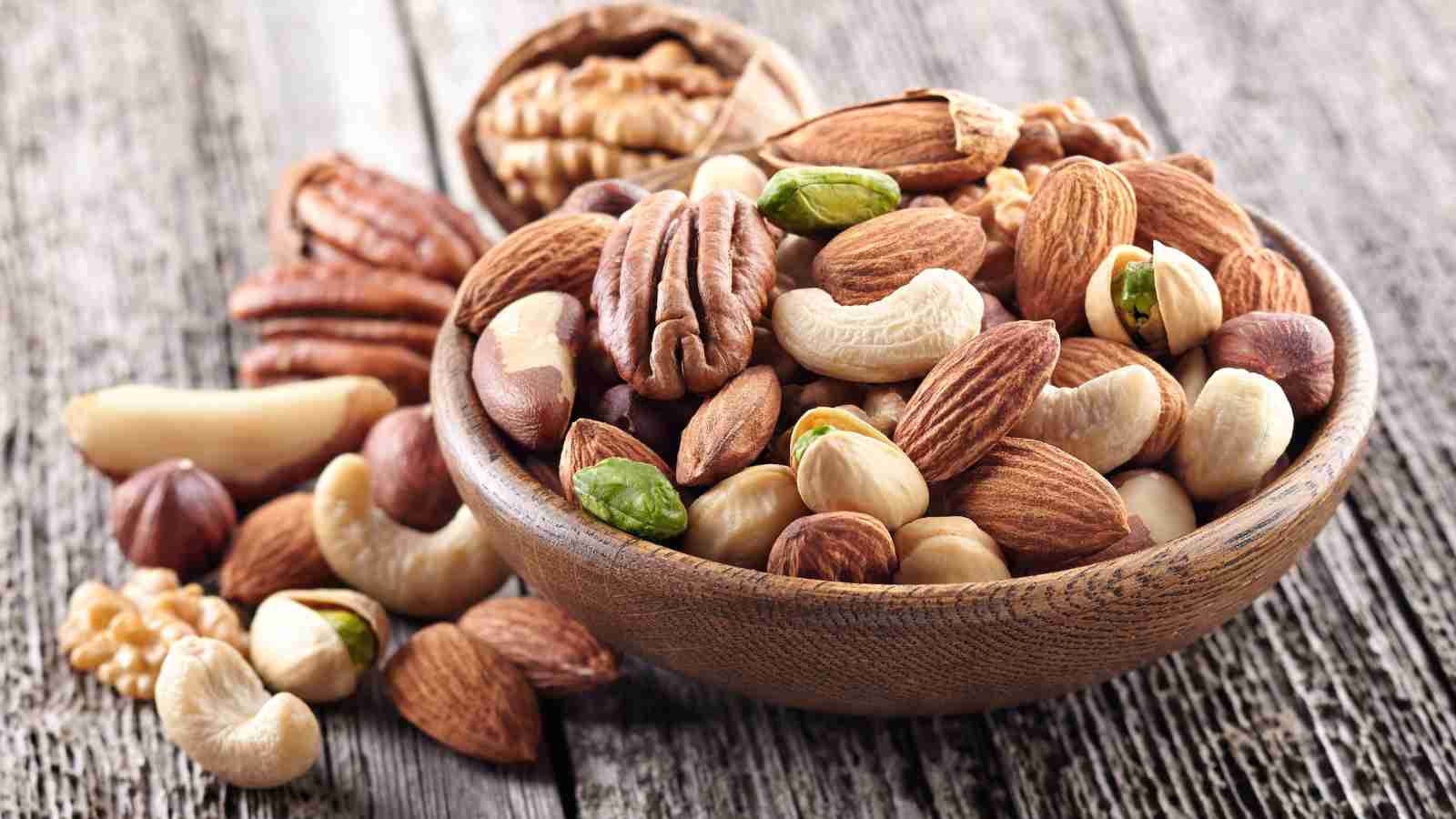 A wooden bowl filled with various mixed nuts.