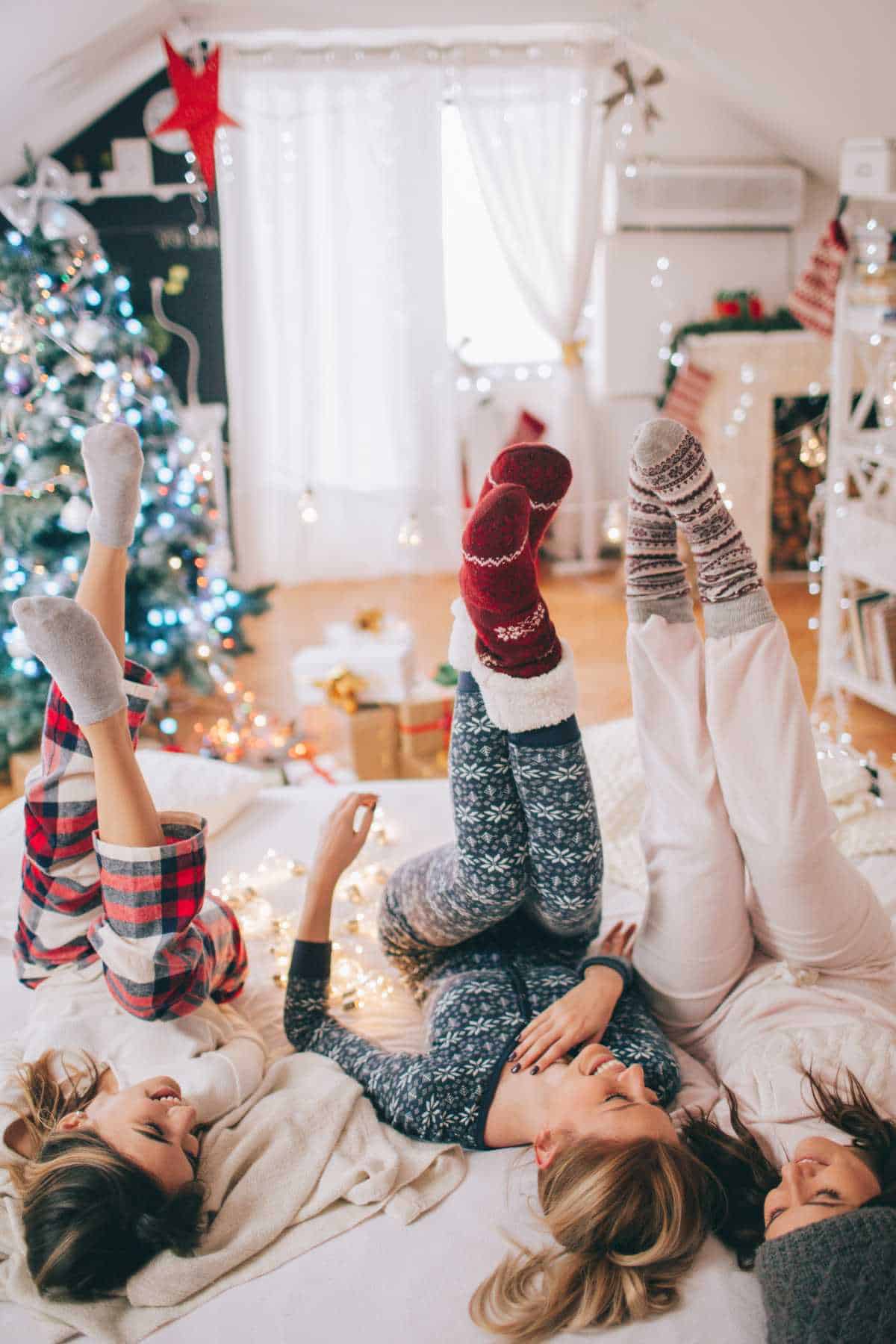 Three people in pajamas lie on a floor with their legs raised.