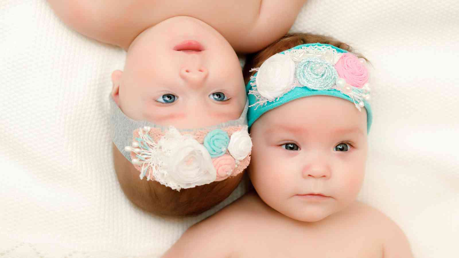 Twin baby girls laying upside down from each other.