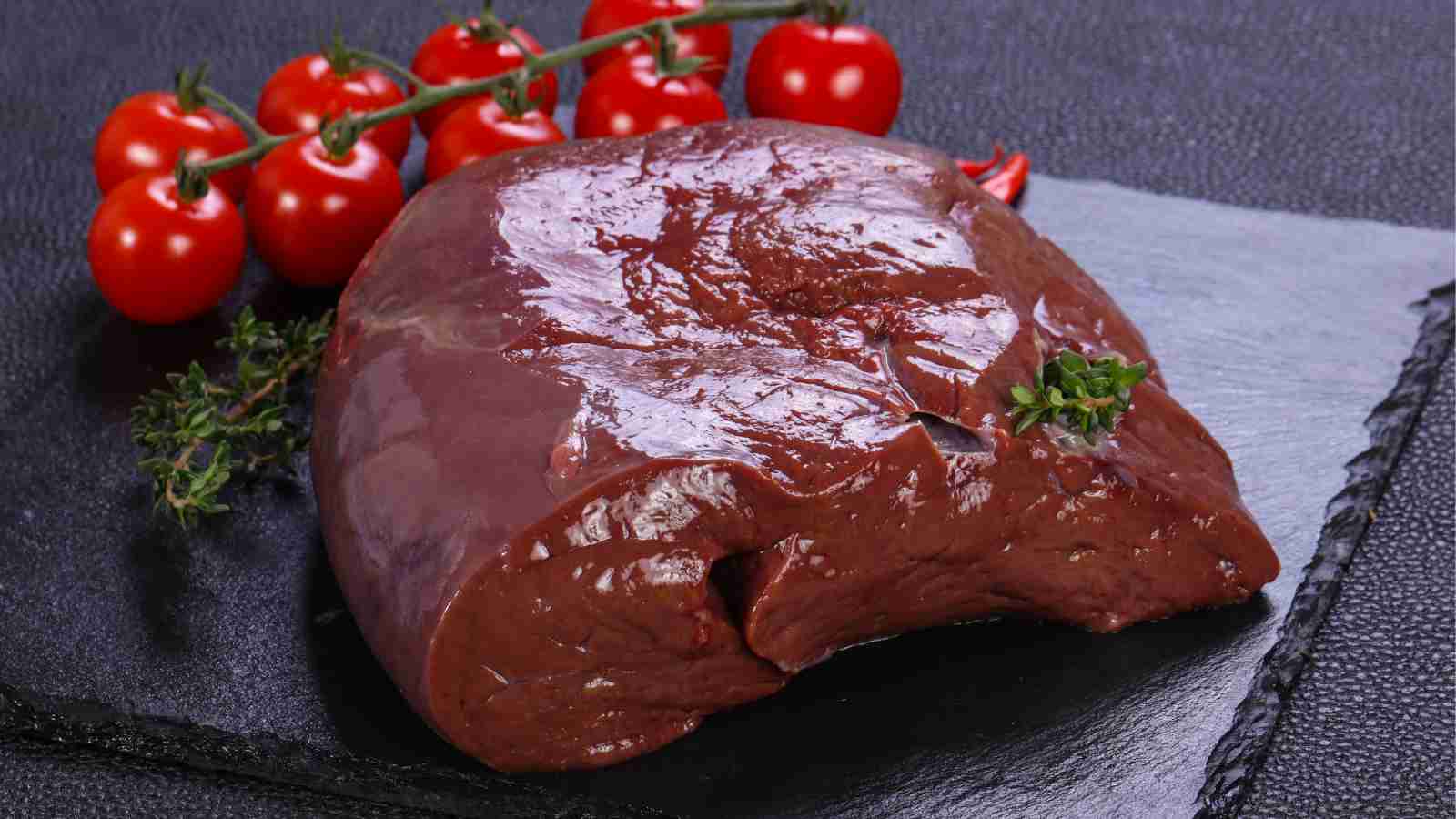 Pork liver on a black surface.